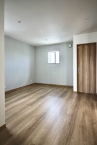 落ち着いた色合いの木目調フローリングと建具が配置された洋室。壁の一面に淡いストライプ柄のアクセントクロスを採用し、シンプルで爽やかに仕上げた空間。