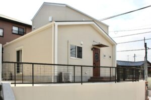 擁壁の上に建てられた、ナチュラルな外観の一戸建て